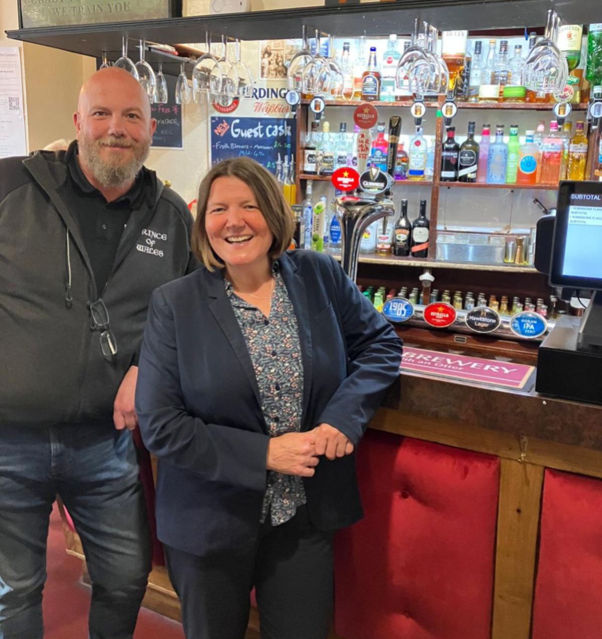 A pub with two people leaning on the bar.
